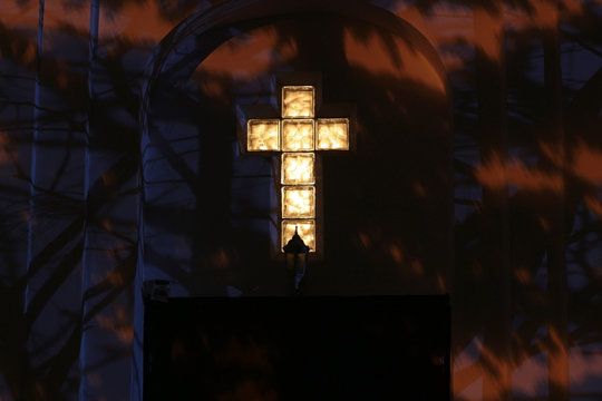 Christian Catholic cross on the facade of the church at night. Black background
