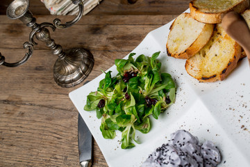 Tasty appetizers with chicken liver pate, valerian salad, toasted bread and blueberry mousse, on an...