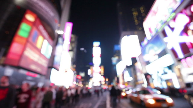 Times Square, New York City, Manhattan background out of focus with blurry unfocused city lights and billboards. City at night with cars and pedestrians people walking.