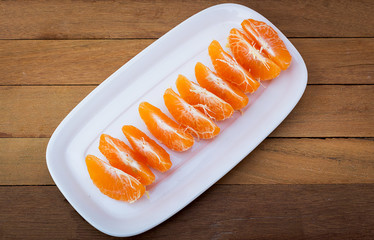 Orange being peeled on plate on the wooden floor.