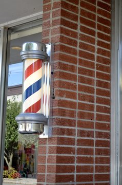 Traditional Barber Shop Pole sign mounted to a brick exterior wall