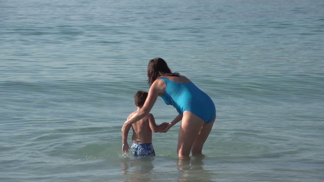 Mother and young boy playing in shallow water on beach,Cape Town,South Africa