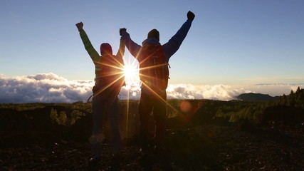 Success, achievement and accomplishment concept with hiking people cheering jumping, running and celebrating of joy on trekking hike outside. Hikers having fun at sunset.