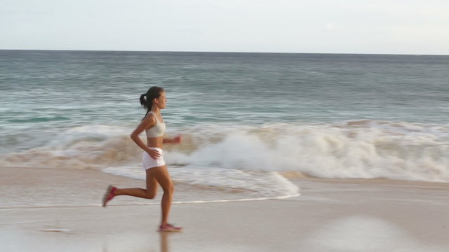 Running woman healthy lifestyle jogging on beach. Female runner training exercising outdoors. Happy fit jogger living healthy lifestyle training outside. Fit mixed race Asian Caucasian fitness girl.