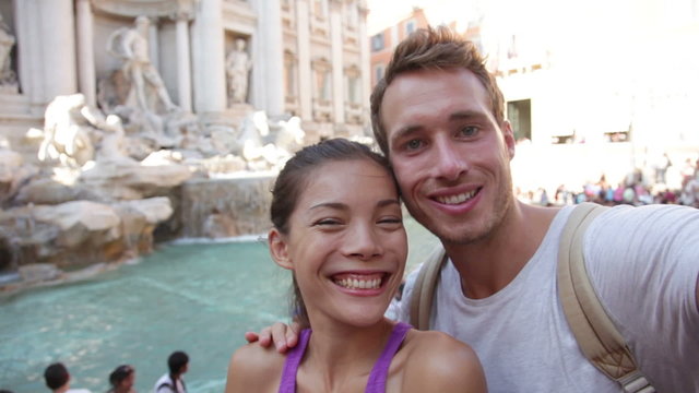 Tourist couple on travel taking selfie photo by Trevi Fountain in Rome, Italy. Happy young romantic couple traveling in Europe taking self-portrait with smartphone camera. Man and woman happy together