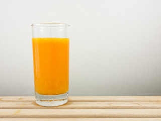 The glass of tasty pure orange juice on wooden tray for a good healthy.