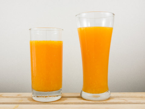 The glass of tasty pure orange juice on wooden tray for a good healthy.