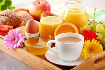 Breakfast on tray served with coffee, juice, egg, and rolls