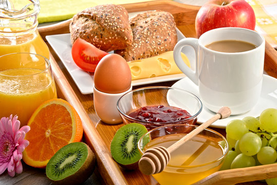Breakfast on tray served with coffee, juice, egg, and rolls