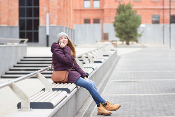 Young woman using a smartphone while sitting outdoors on a bench