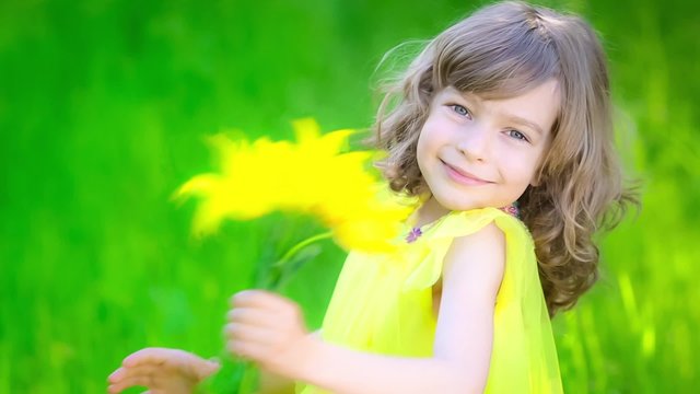 Happy child with bouquet of flowers against green background. Spring family holiday concept. Mother's day. Slow motion