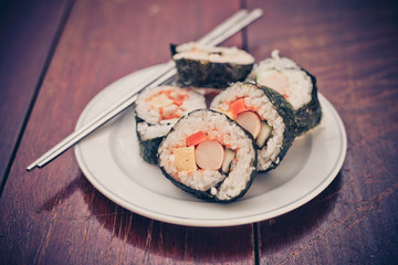 Close up of Rolled sushi rice on a white dish , Dark Vintage color filter