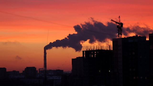 Rubber products plant emitting steam during red sunset