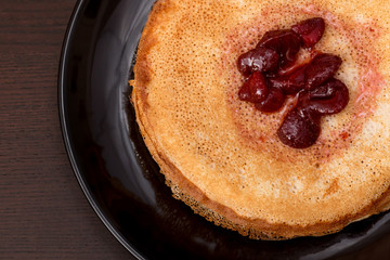 Pancakes with strawberry jam on a black plate