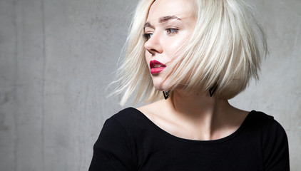 Close-up portrait of a beautiful blonde with red lips on a black background
