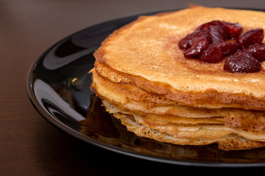 Pancakes with strawberry jam on a black plate