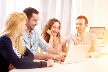 Group of 4 young attractive people working on a laptop