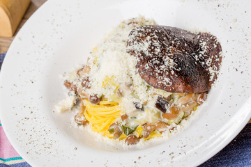 Tasty spagetti with honey fungus and shiitake mushrooms on an old wooden table