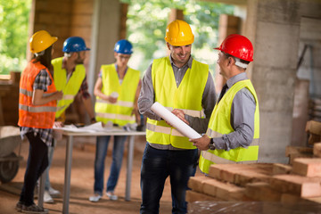 Architect and investiture handshaking on construction site