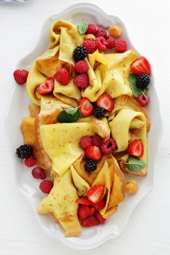 crepes with fresh berries on white plate