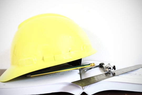 hard hat with pencil compasses and rulers/book on table and wall