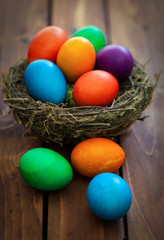 colorful Easter eggs in the nest on the old wooden background