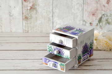 A handmade chest of trinket drawers decoupaged with vintage paperwith pots of Lavender on a rustic wooden background - obrazy, fototapety, plakaty