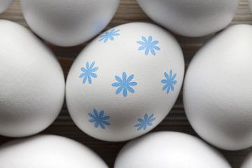 One egg with blue pattern and many white eggs