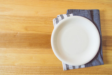 Empty plate and towel over wooden table background