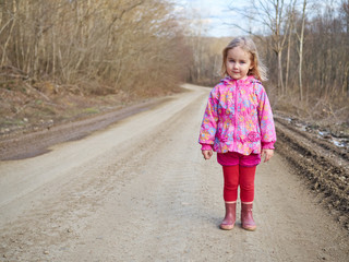 Cute little girl standing on a forest road