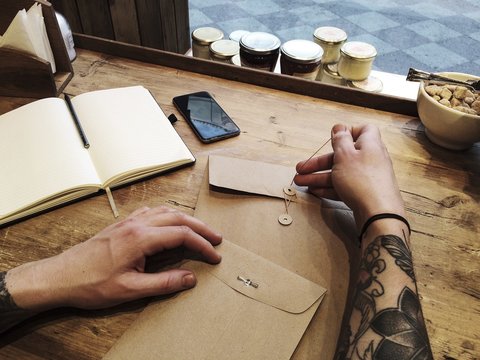 Man in cafe works with notebook, tattoo hands