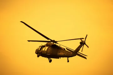 Wall murals Silhouette of the military helicopter  moving into sky at sunset