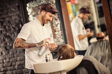 Hairstylist washing head of man with beard.