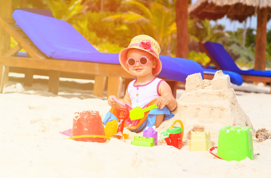 cute little girl building sandcastle on beach