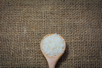 Rice with wooden Spoon on sack background