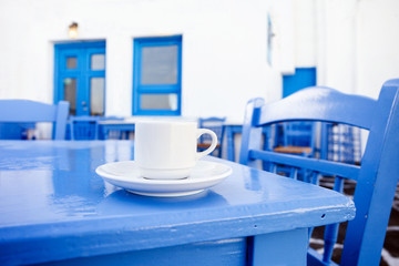 A cup of coffee on table with Greek street at the background
