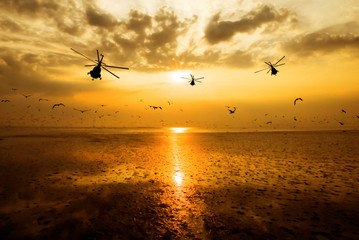 Fototapeta na wymiar Silhouette of the military helicopter moving into sky at sunset