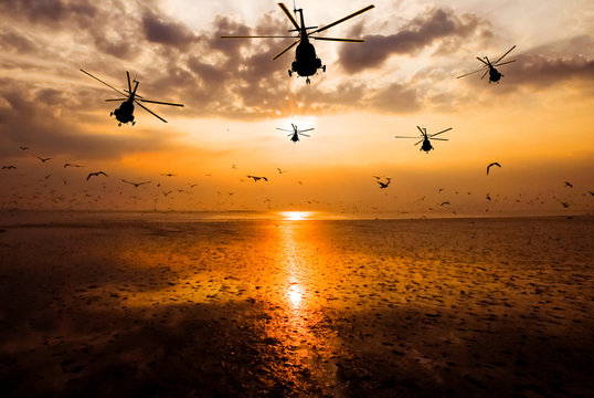 Silhouette of the military helicopter  moving into sky at sunset