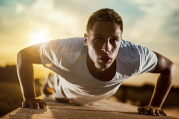 Young athletic man doing push ups outdoors