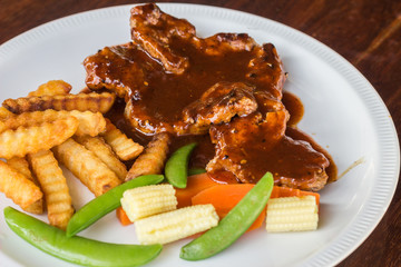 Grilled pork steak, French fries and vegetables