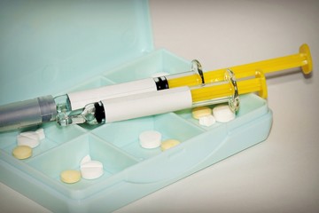 Syringes and pills on white background