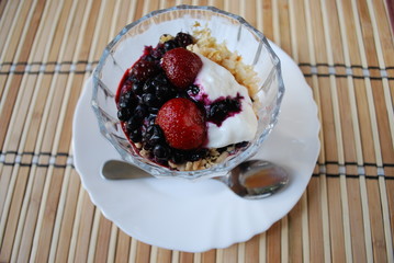 Berries (strawberries, blueberries, blackberries) dessert with yogurt and rice flakes in glass cup. Finished dish.