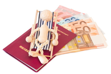 Reisepass mit Holzpuppe auf Liegestuhl und Geld