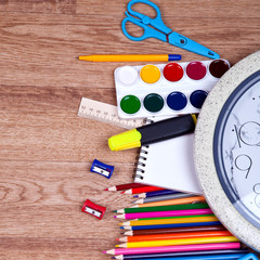 school supplies and checked notebook on wood background
