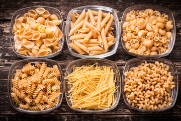Various mix of pasta on wooden rustic background. Diet and food