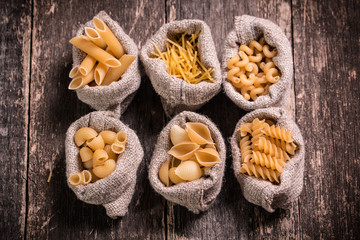 Various mix of pasta on wooden rustic background. Diet and food