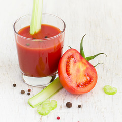 Tomato juice in glass with celery on a white background