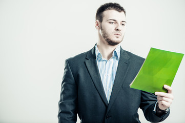 businessman exploring info from green booklet