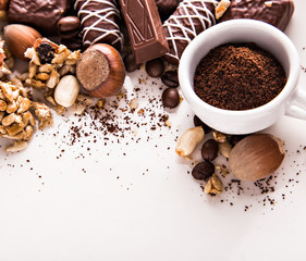 Roasted coffee beans, chocolate, candy, nuts, cup and the place for inscriptions on white background