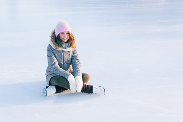 Ice skating woman sitting on the ice smiling